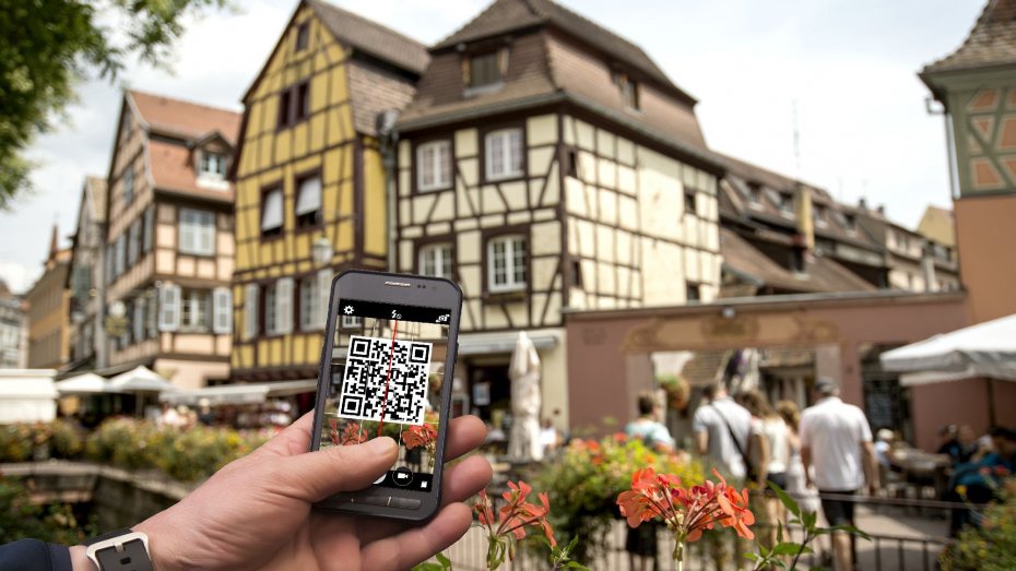 Smartphone mit QR-Code vor Altstadtgebäuden
