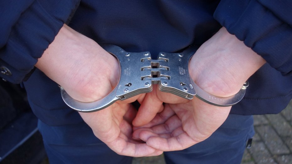 Person mit durch Handschellen hinter den Rücken gefesselten Händen