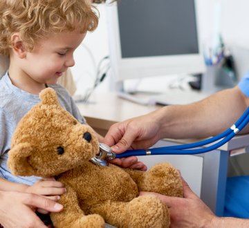 Kind mit Teddybär beim Kinderarzt