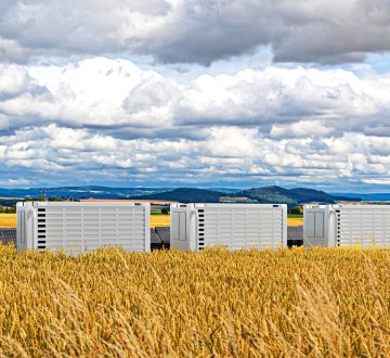 Symbolbild: Batteriespeicher und Solaranlagen an einem Feld